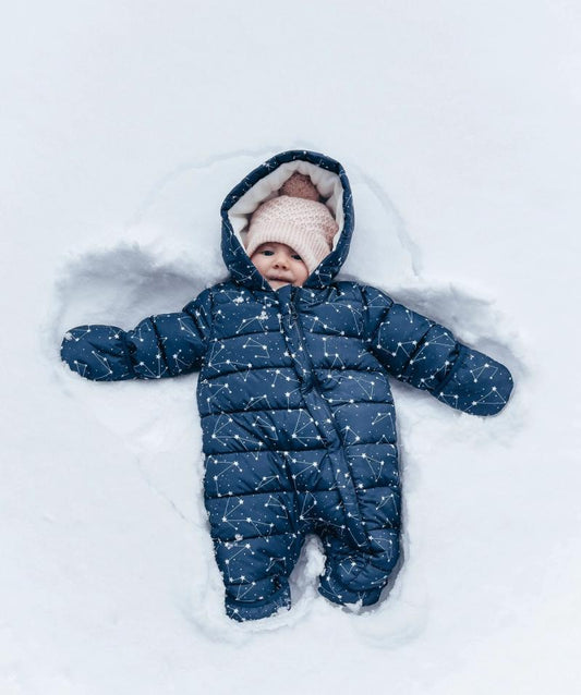 baby in a blue suit making a snow angel